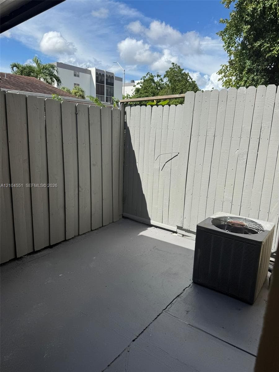 Private outdoor patio featuring painted wood fencing and a concrete floor