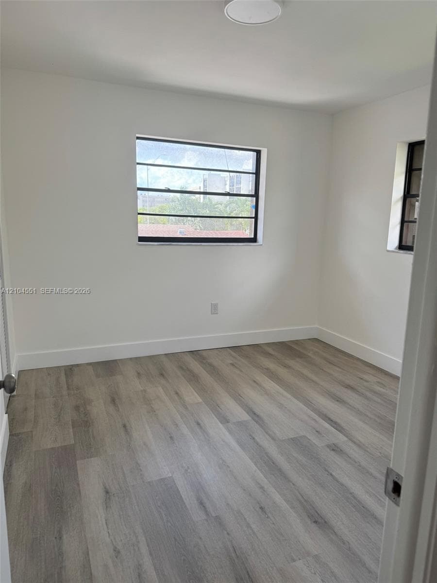 Neutral-toned wood-finish flooring, crisp white walls, and horizontal-pane windows with dark frames