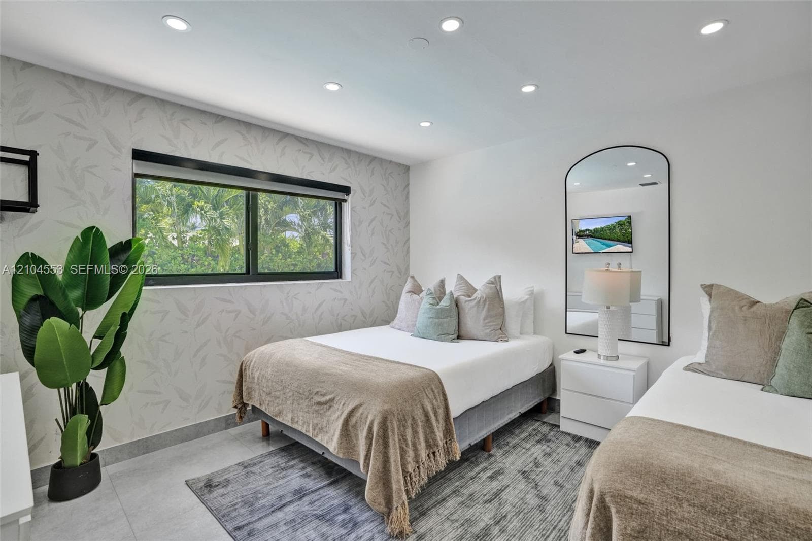 Neutral-toned wallpaper, recessed ceiling lighting, light-colored tile flooring, and an arched wall mirror