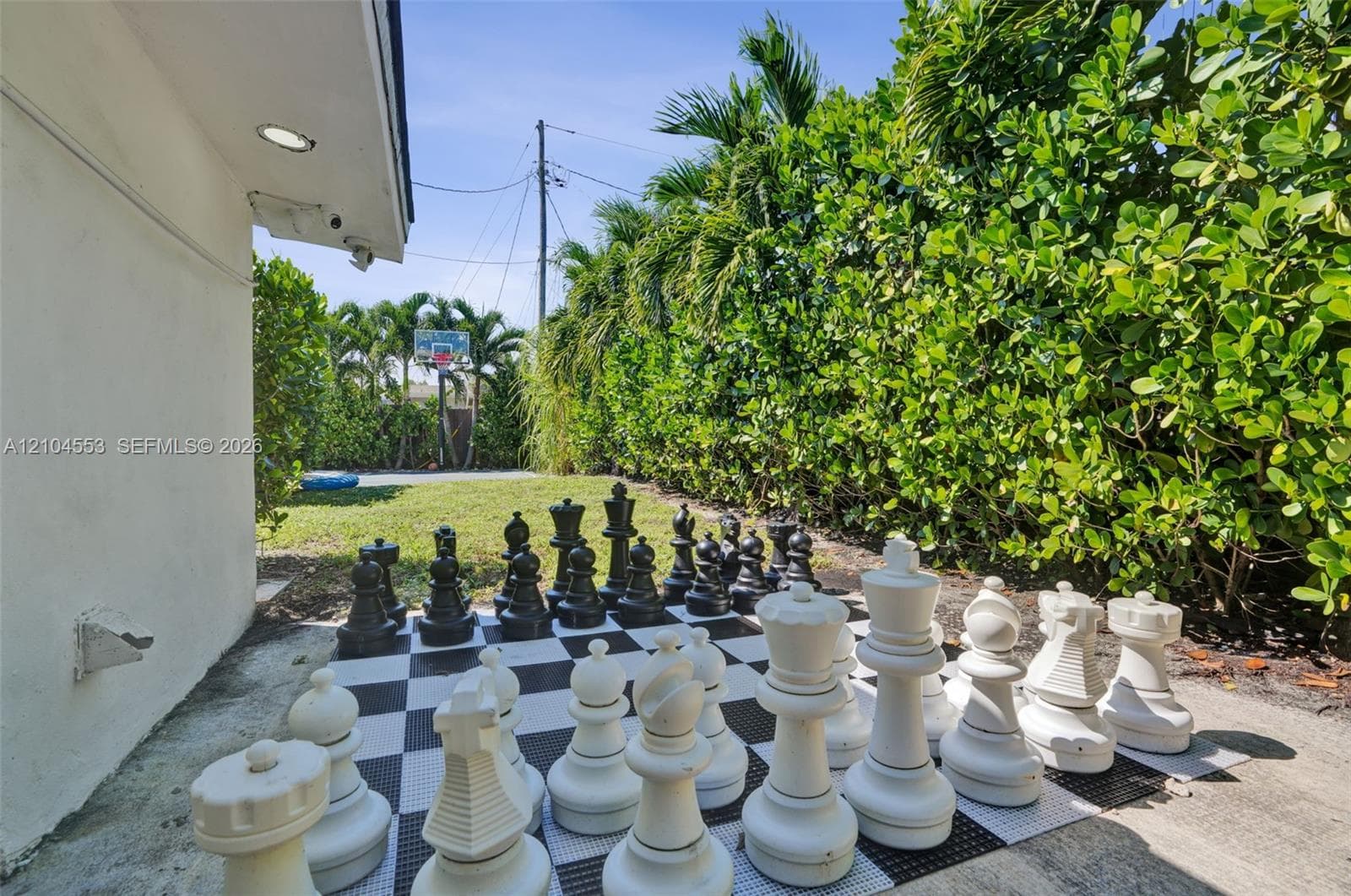 Expansive backyard featuring a concrete patio, integrated lawn space, and a mature perimeter privacy hedge