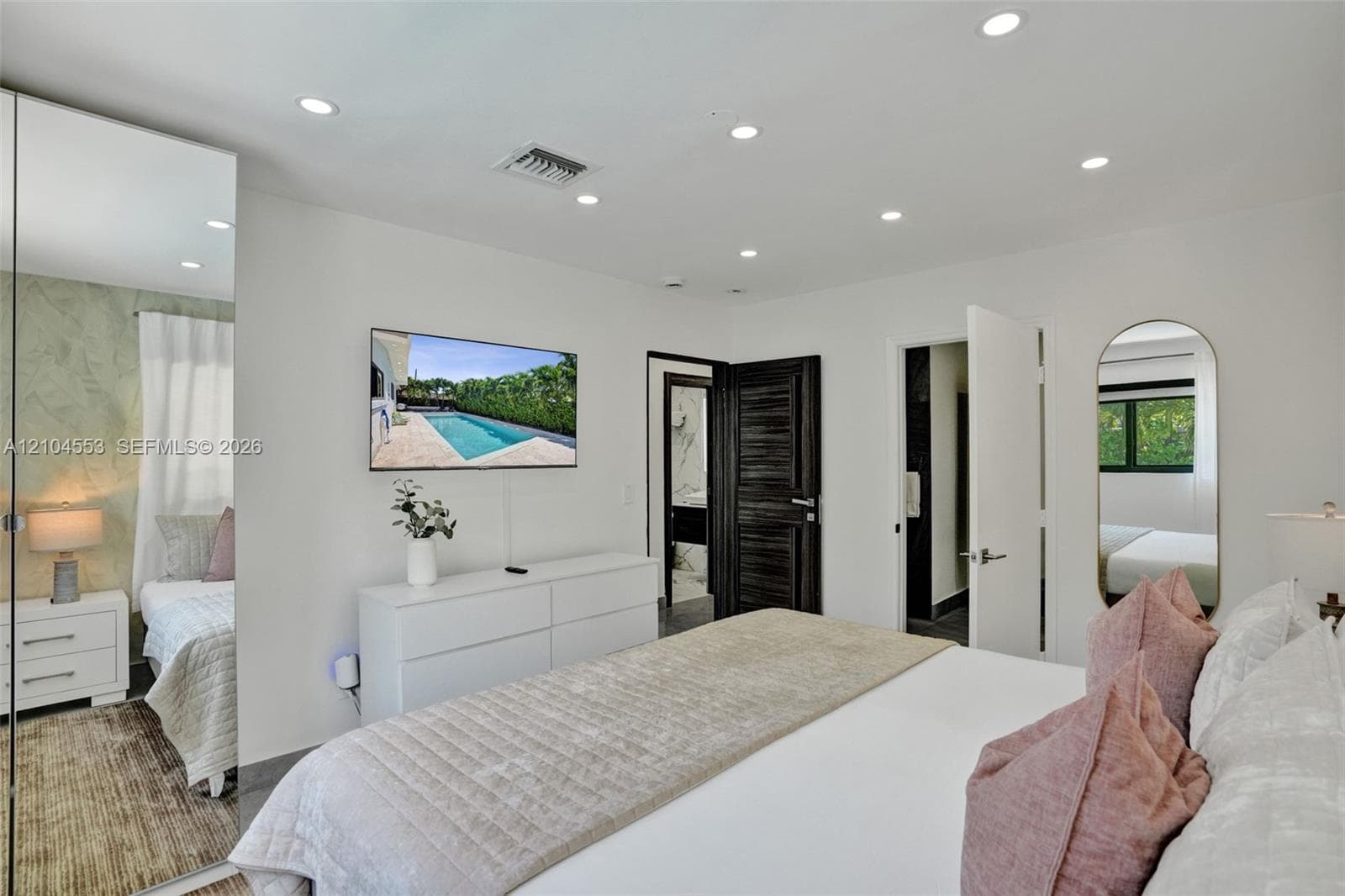 Full-height mirrored wall panel, recessed ceiling lighting, arched wall mirror, and dark-finished interior door