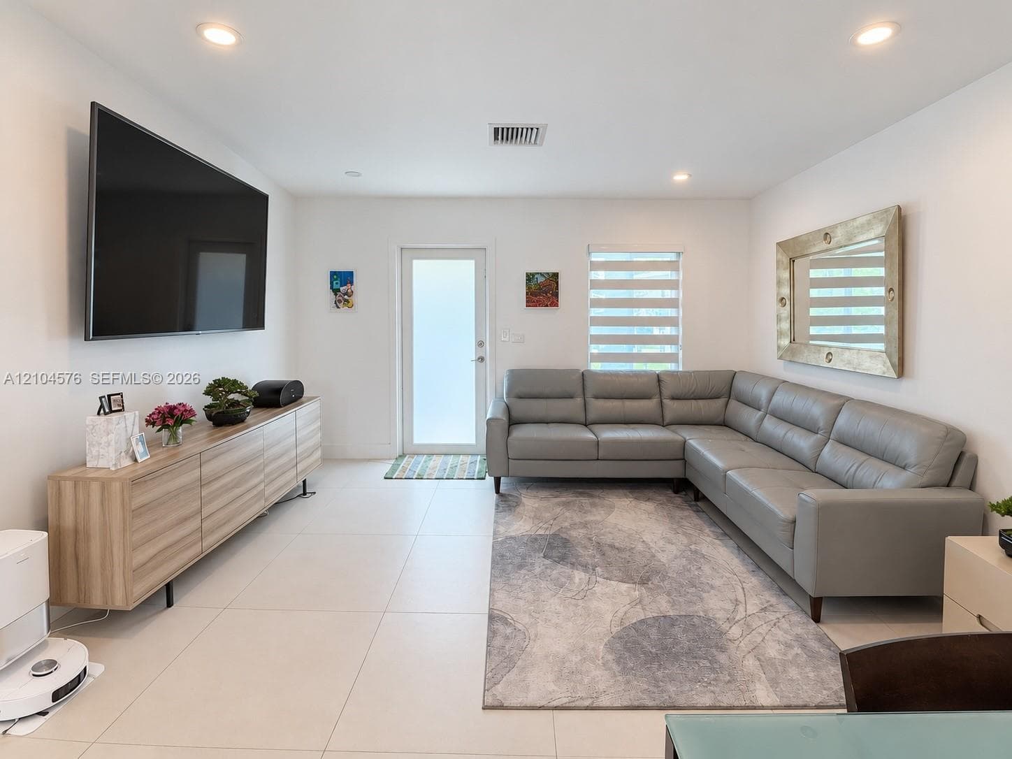 Large-format tile flooring, recessed lighting, and dual-shade window coverings featuring a glass-panel entry door