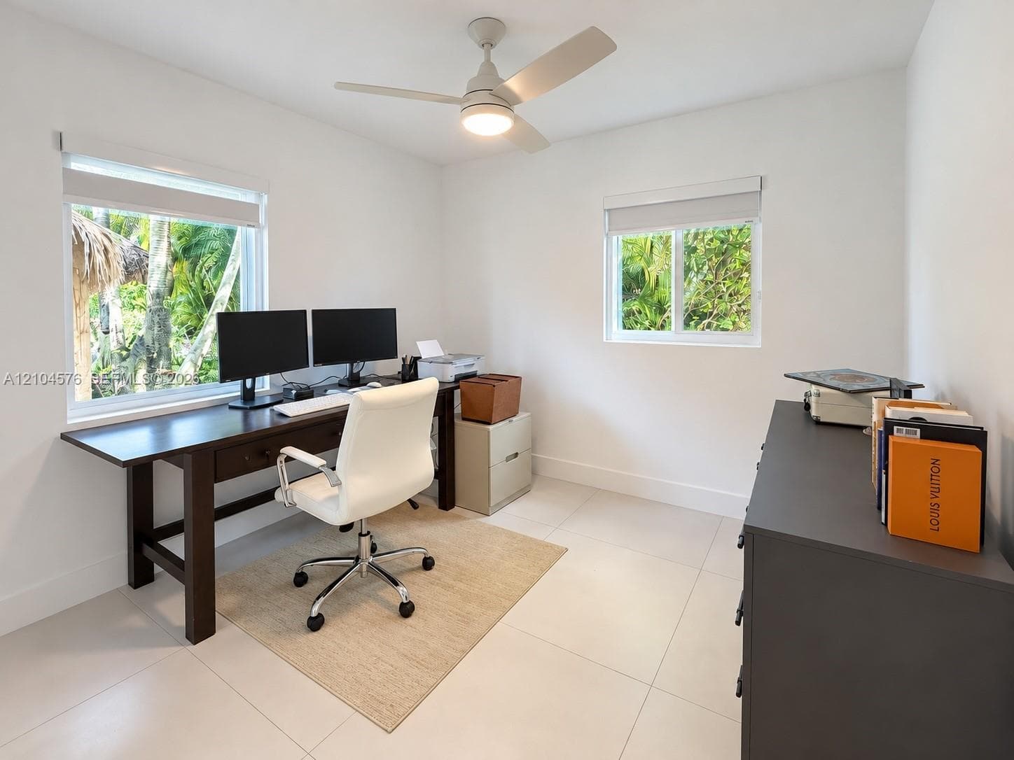 Bright interior featuring large windows, neutral tile flooring, and an integrated ceiling fan with a central light fixture