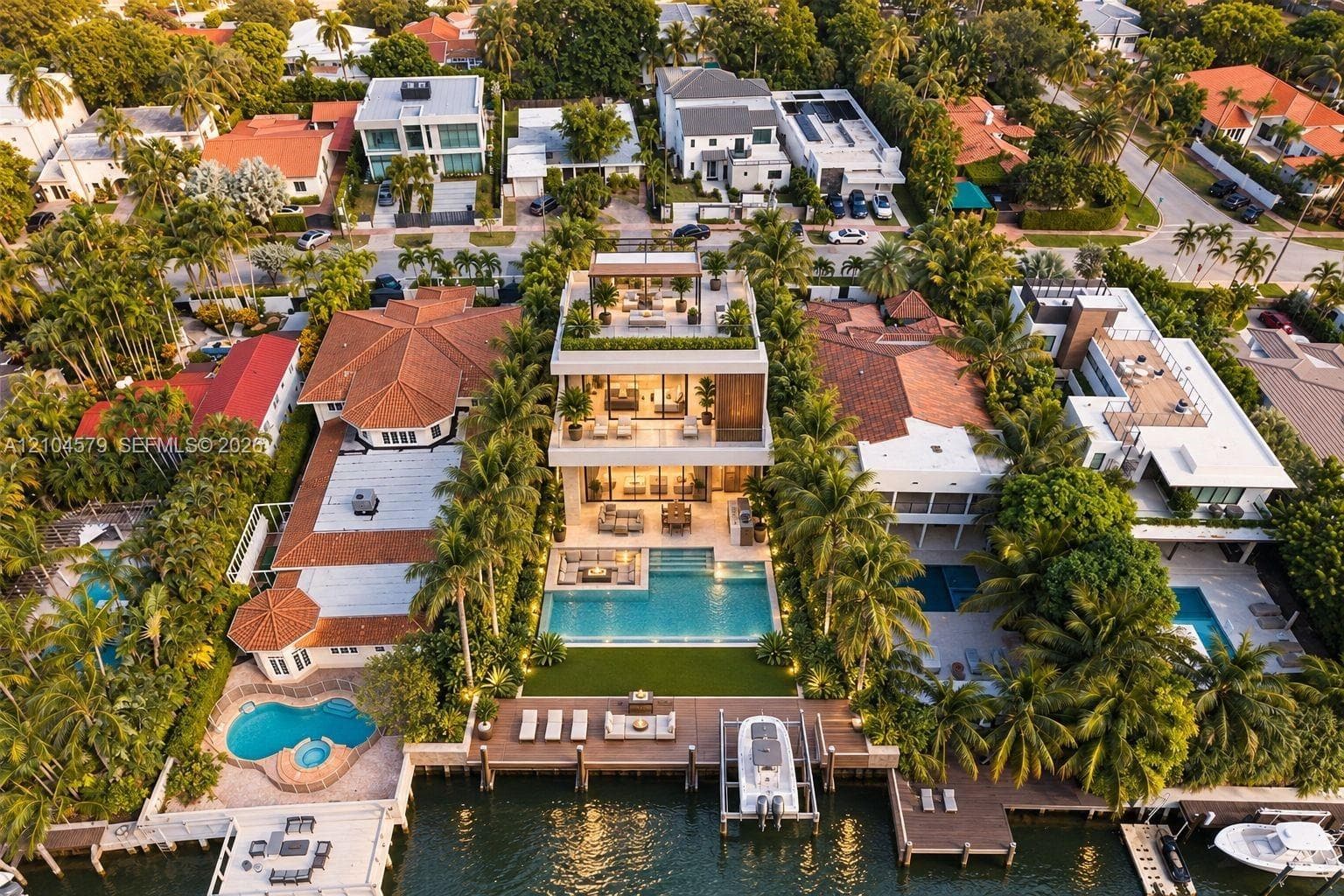 Modern waterfront residence featuring multiple balconies, a rooftop deck, an expansive private pool, and private boat dockage