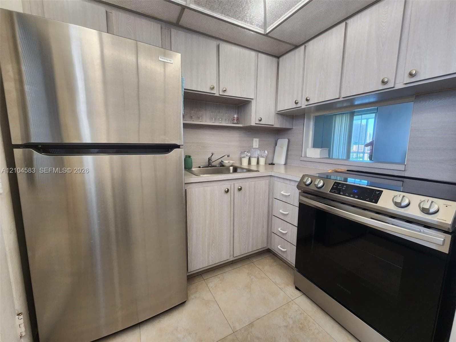 Kitchen featuring wood-finish cabinetry, stainless steel refrigerator, stainless steel range, and tile flooring