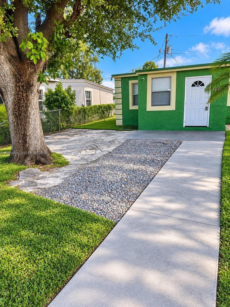 Exterior featuring a concrete walkway, crushed stone driveway, and mature tree landscaping