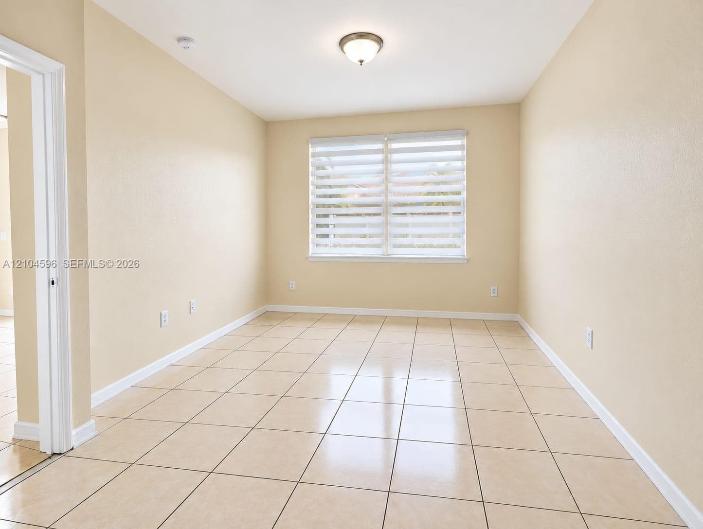Room featuring ceramic tile flooring, neutral wall paint, and dual-layered window shades