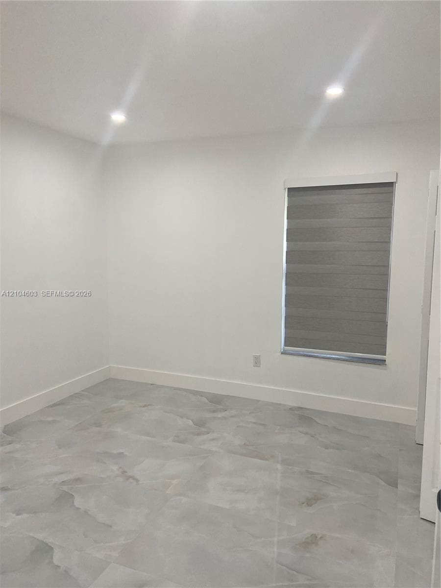 Recessed ceiling lighting, wide baseboards, and patterned tile flooring