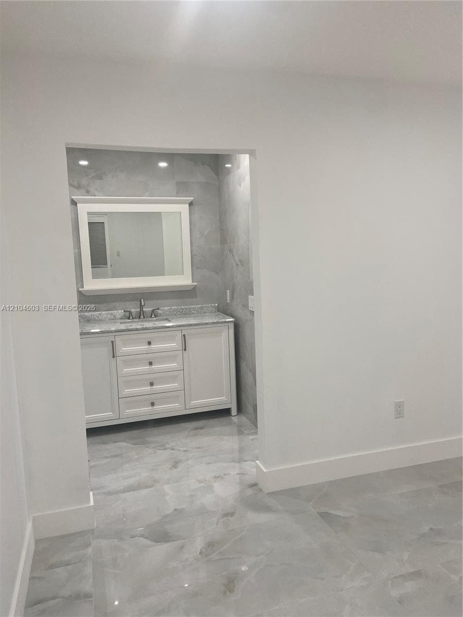Vanity with a light-toned countertop, integrated sink, and white cabinetry