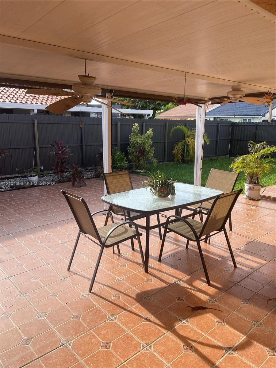 Expansive patio featuring a tiled surface and a covered awning with ceiling fans