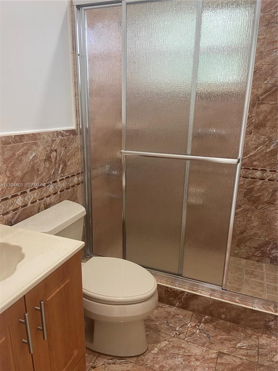 Shower enclosure with textured glass, sliding doors, and a metal frame