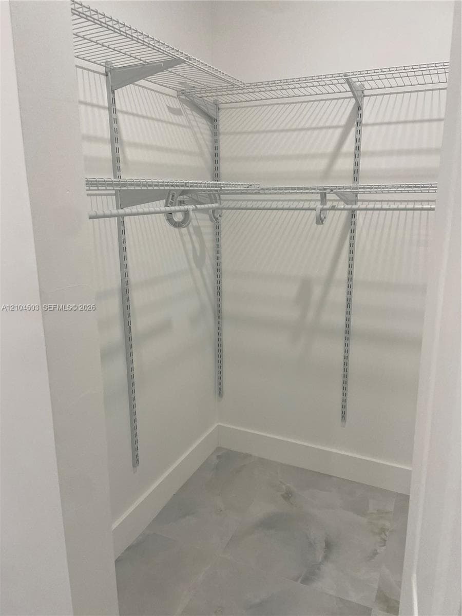 Walk-in closet featuring wire shelving, multiple hanging rods, and light-toned flooring