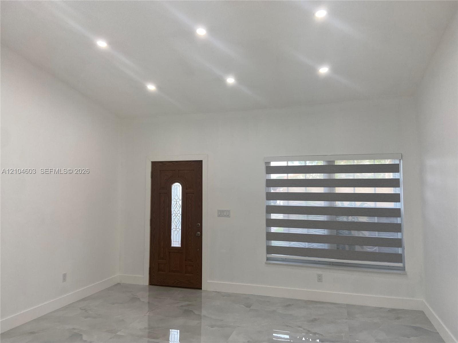 Recessed ceiling lighting, patterned window blinds, decorative entry door with glass insert, and polished tile flooring