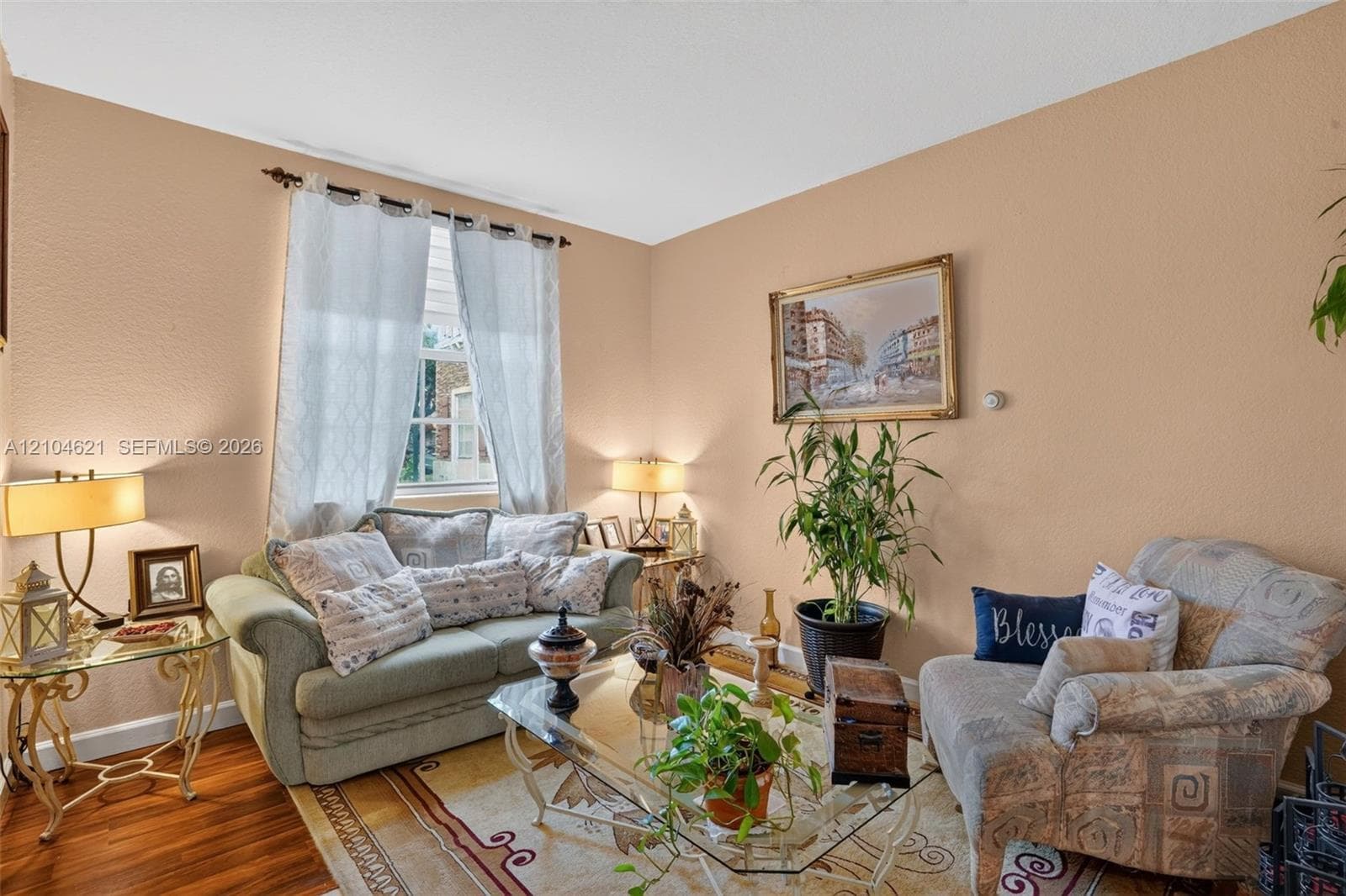 Interior space featuring neutral-toned walls, wood-finish flooring, and a window with a rod-mounted curtain treatment
