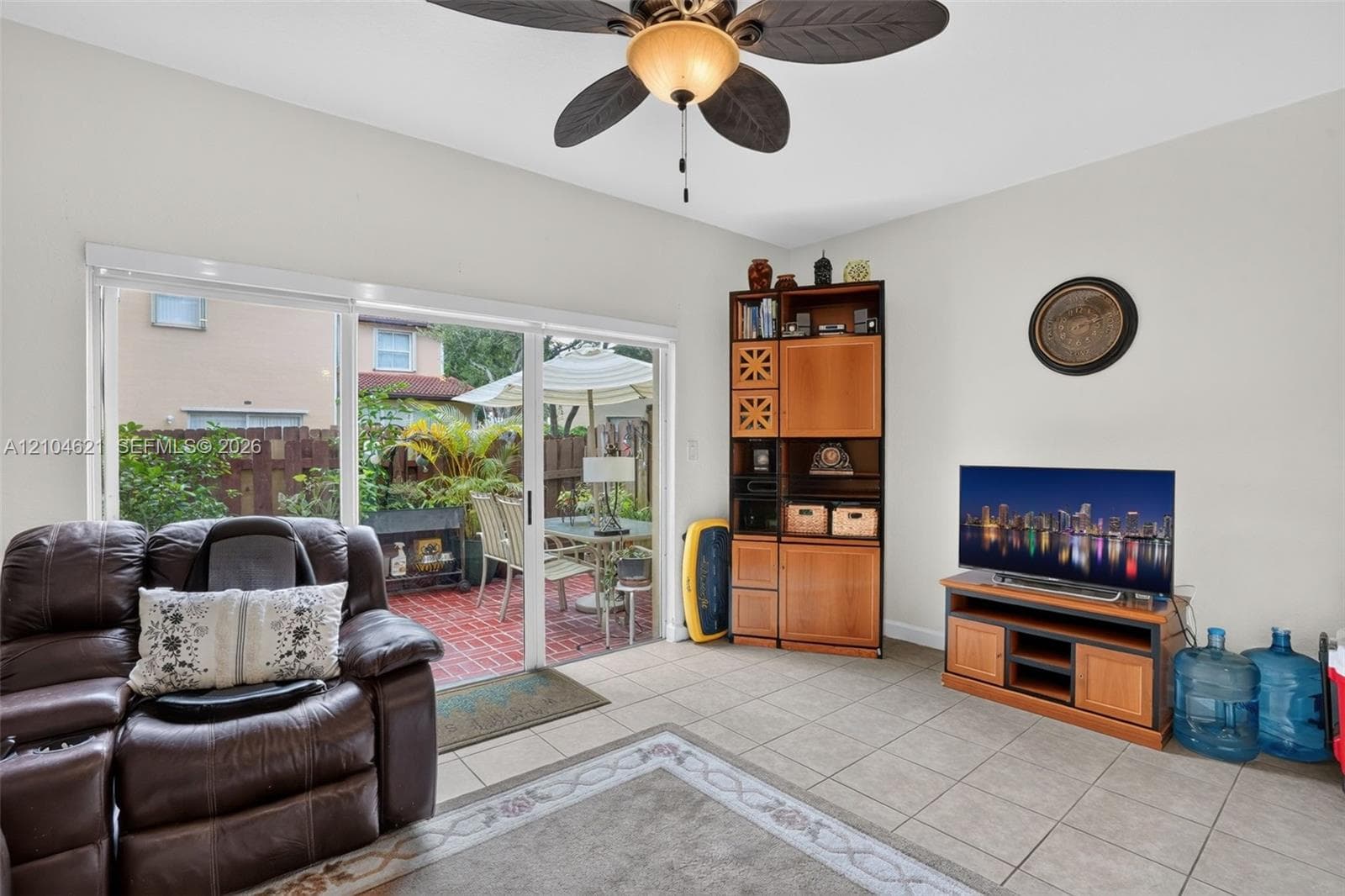 Interior featuring large-format tile flooring, sliding glass patio doors, and a ceiling-mounted light fixture with a multi-blade fan