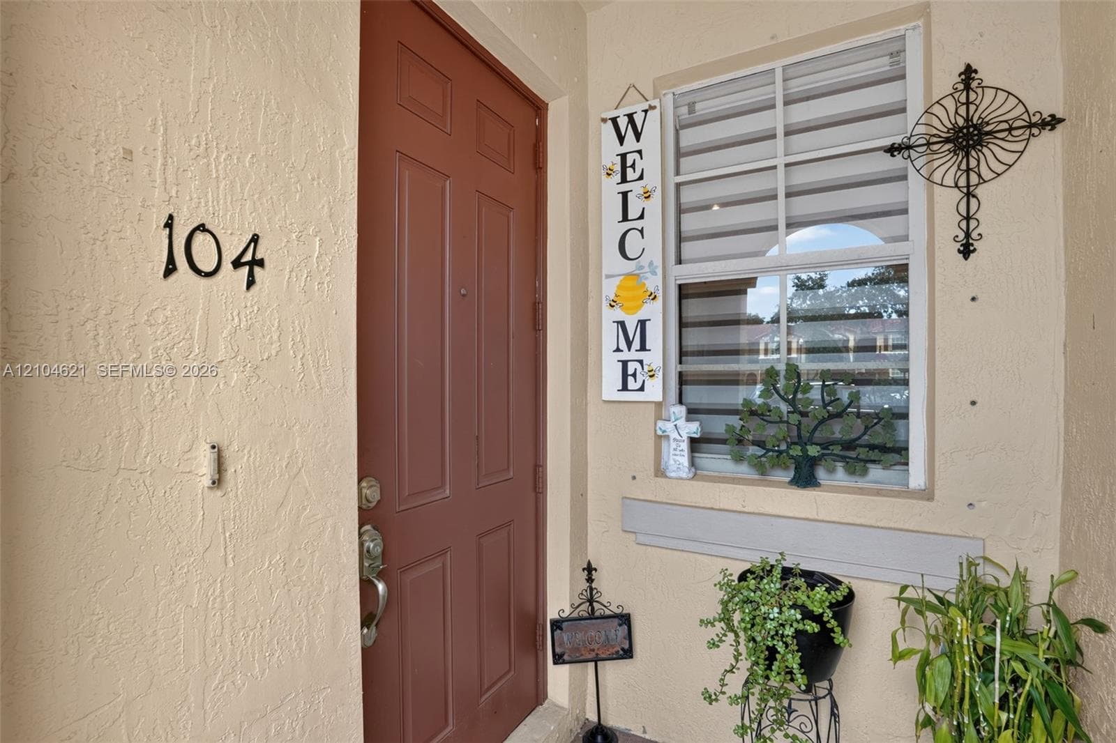 Entryway featuring a solid panel door, stucco exterior finish, and a window with horizontal blinds