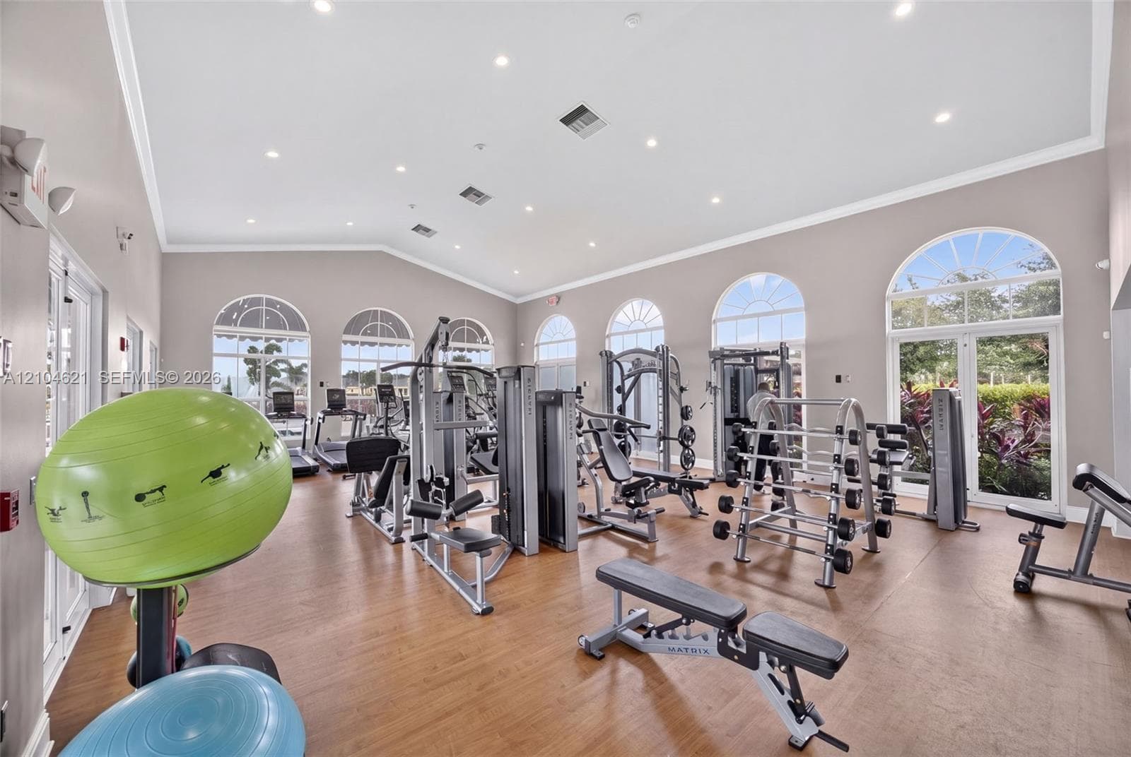 Fitness center featuring wood-finish flooring, vaulted ceilings, recessed lighting, and multiple arched windows