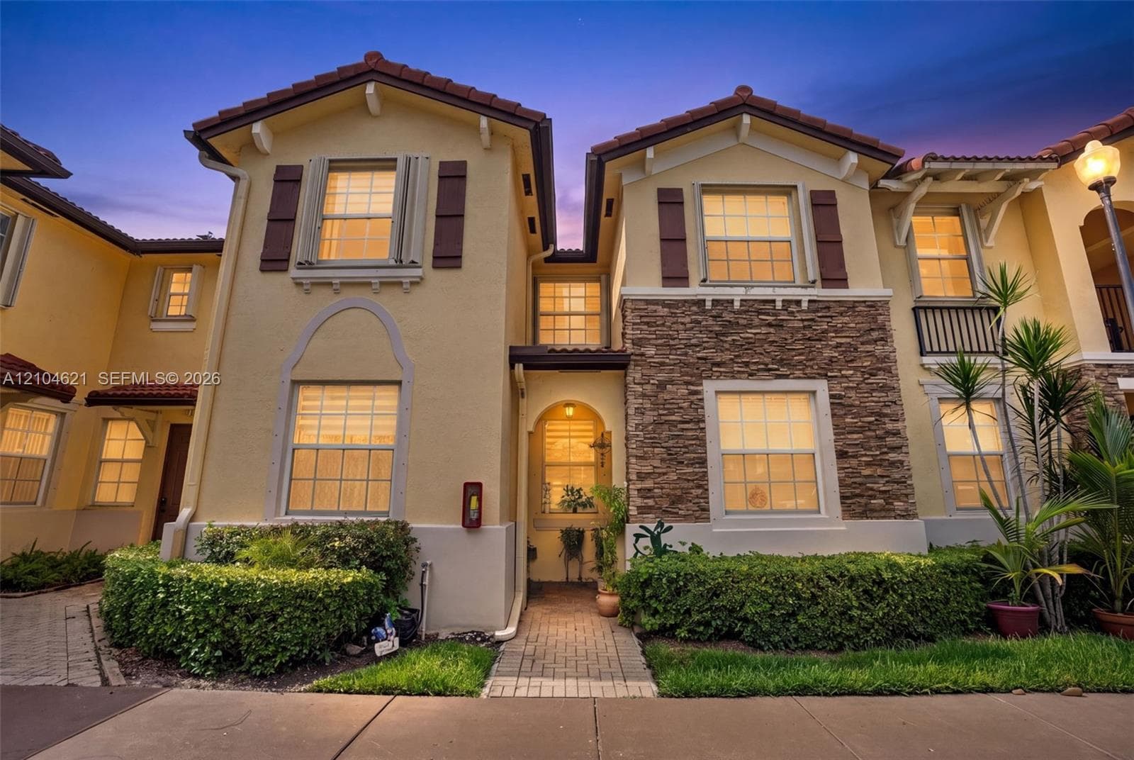 Stucco exterior with stone veneer accents, multi-gabled tile roofline, and decorative window shutters