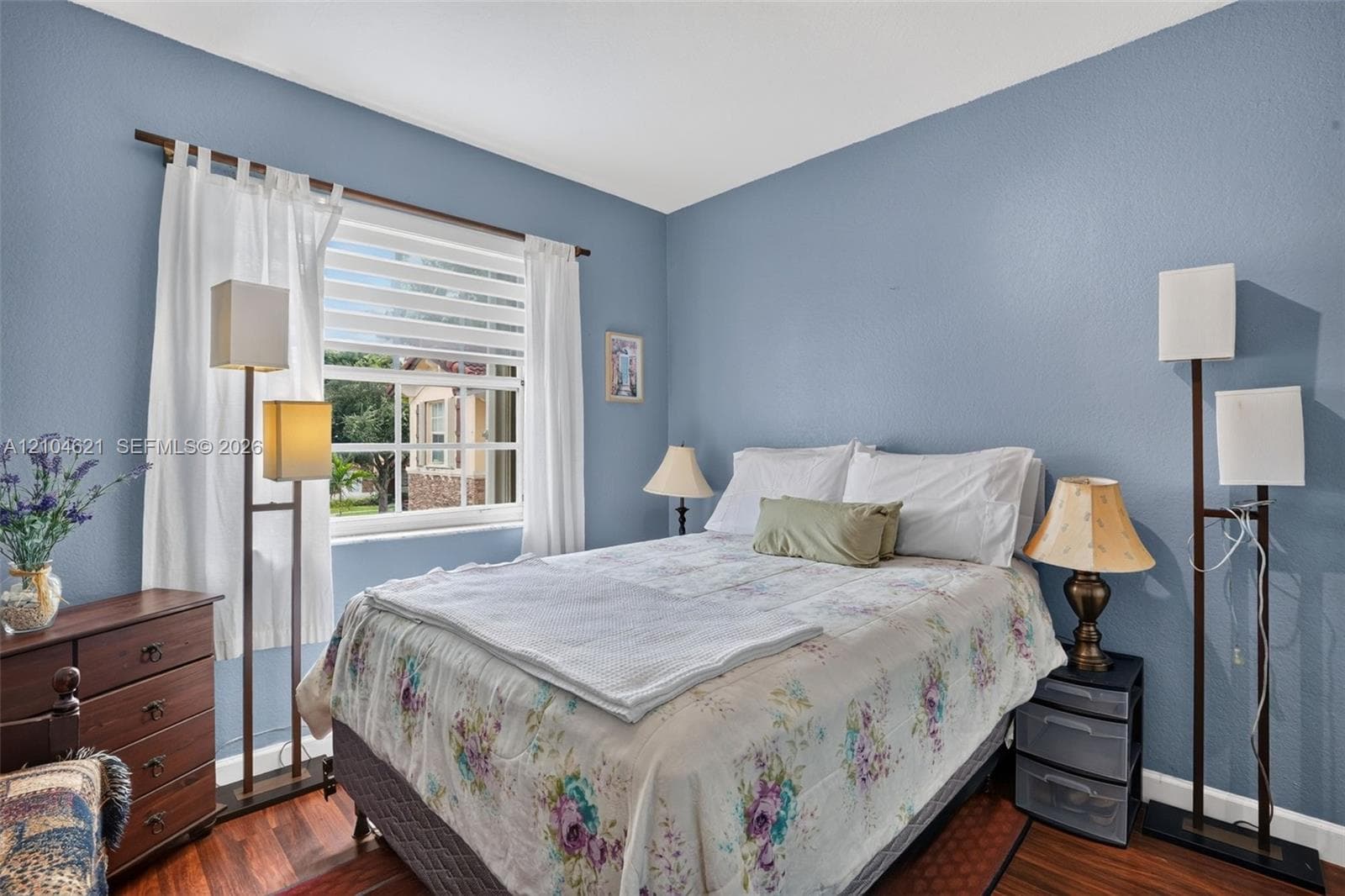 Room featuring wood-finish flooring, textured walls, and a multi-pane window with horizontal blinds
