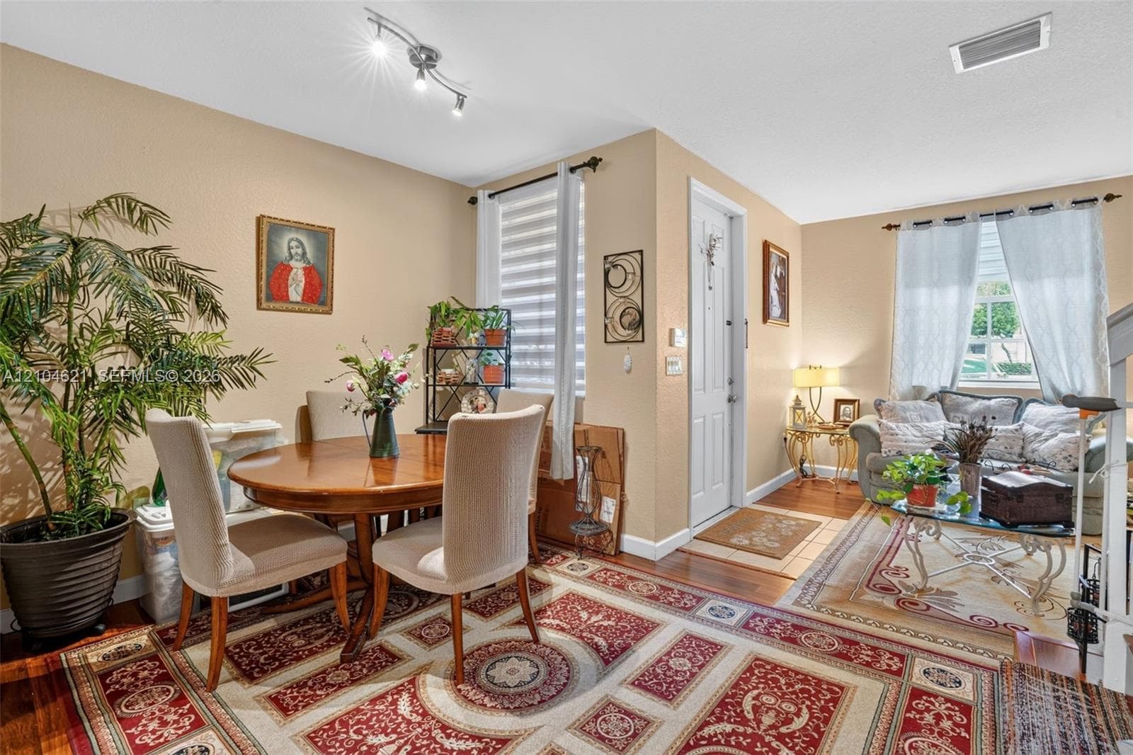 Open-concept interior featuring wood-finish flooring, multi-directional track lighting, and windows outfitted with dual-layered light-filtering shades