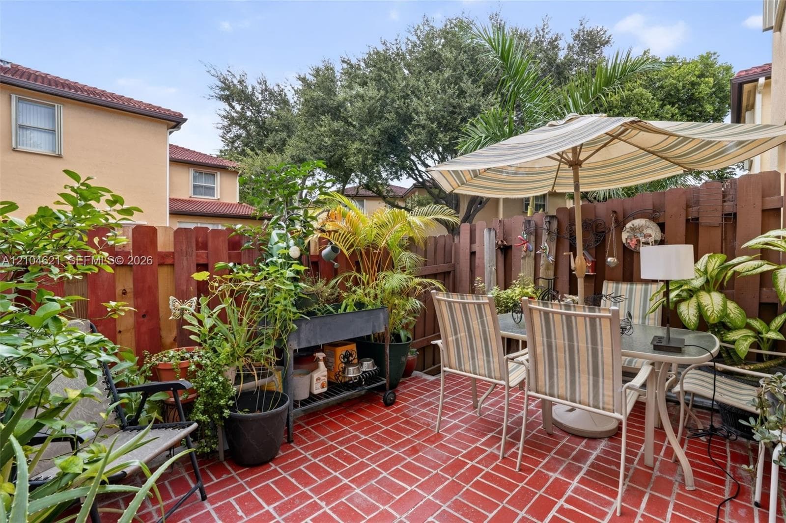 Enclosed patio featuring red masonry tile flooring and wood privacy fencing