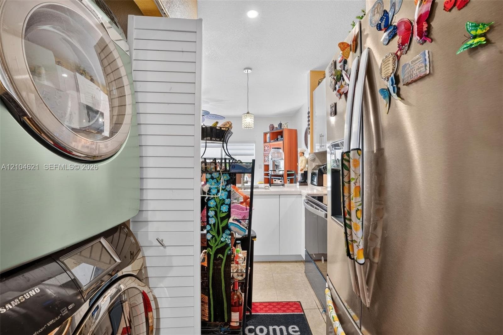 Stacked laundry appliances, stainless steel refrigerator, white louvered door, and recessed ceiling lighting