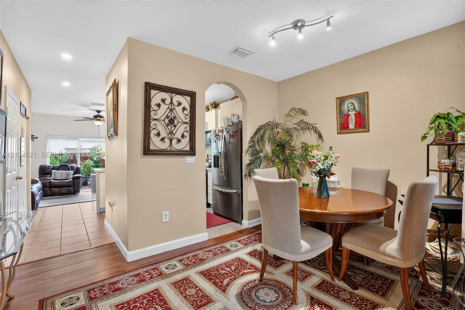 Dining area featuring wood-finish flooring, an arched entryway, and modern track lighting