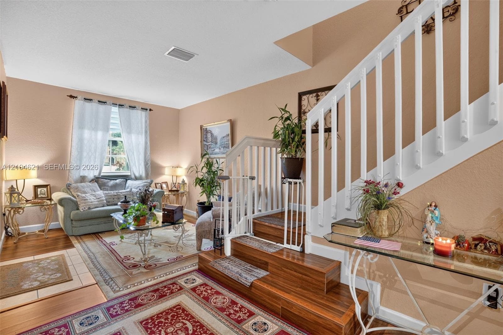 Interior space featuring a staircase with wood-finish treads, white wooden balustrade, tile flooring, and large window with natural light