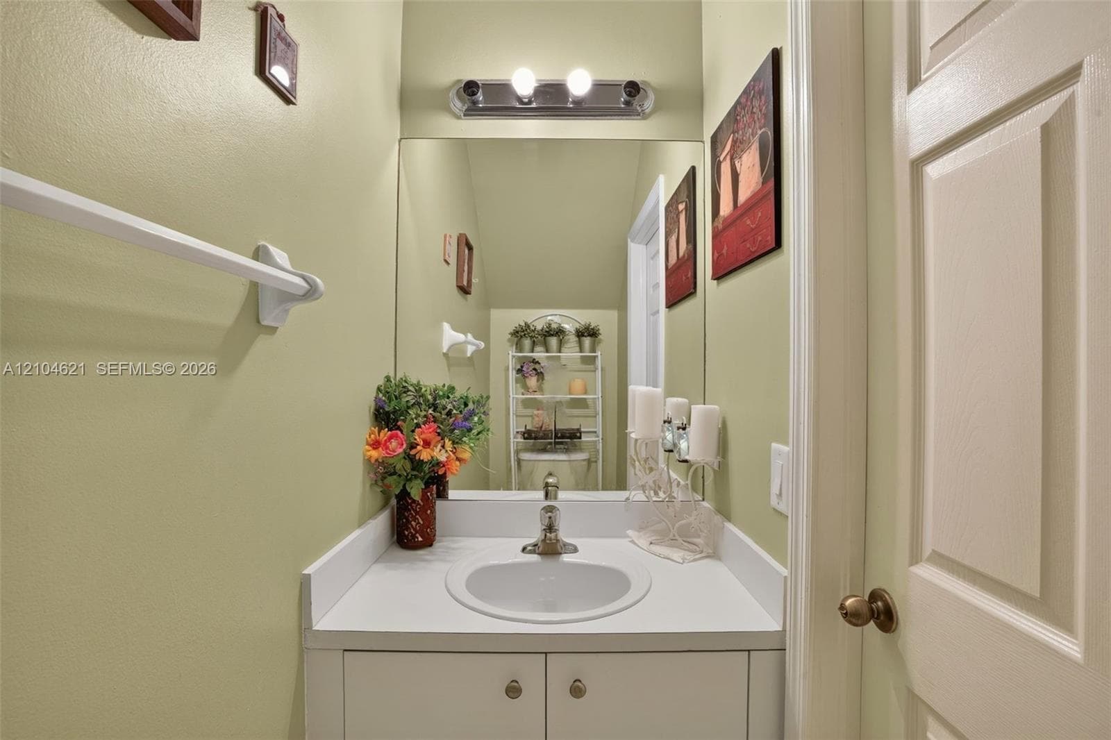 Vanity featuring a white countertop with an integrated oval basin, built-in lower cabinetry, a large wall-mounted mirror, and a multi-bulb light fixture