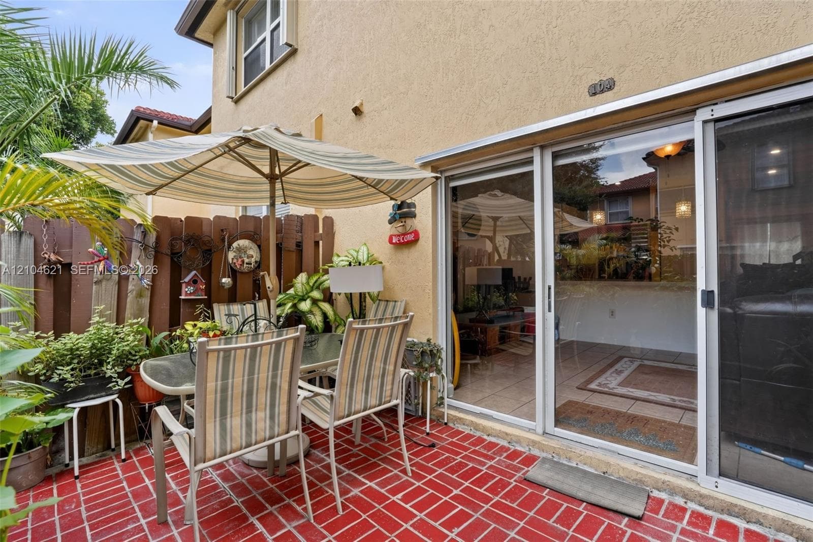 Enclosed patio featuring red ceramic tile flooring, vertical wood privacy fencing, and dual sliding glass doors