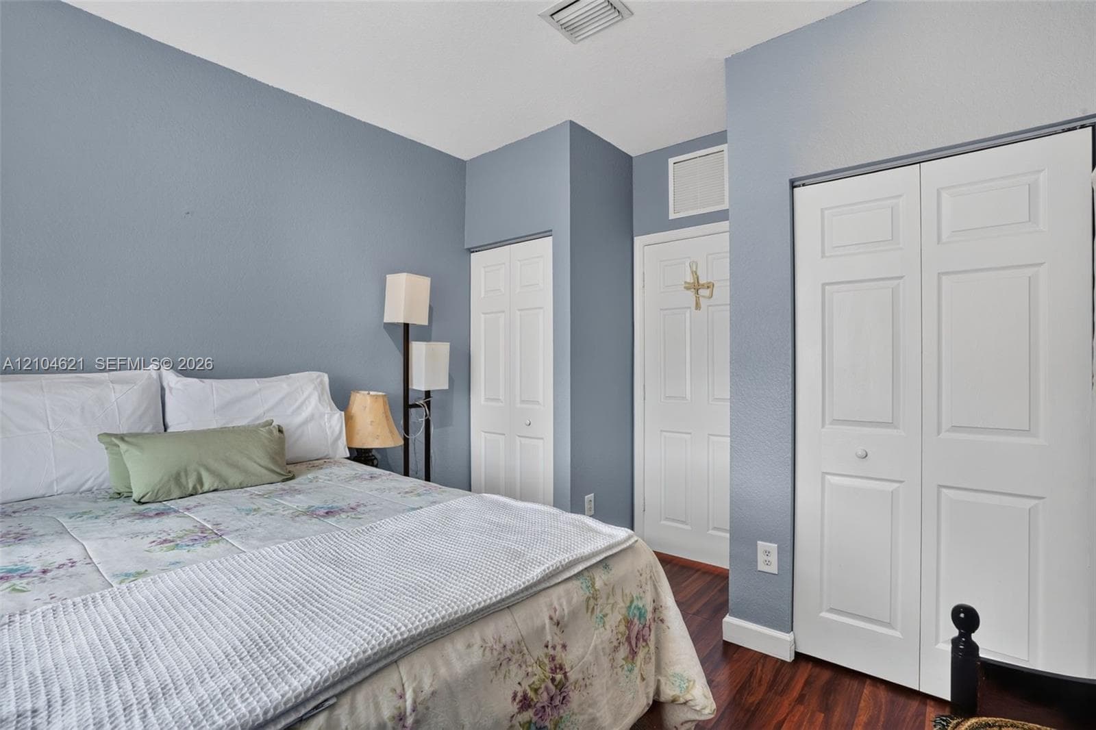 Interior space featuring wood-finish flooring, two sets of white six-panel closet doors, and a single solid core door with a white finish