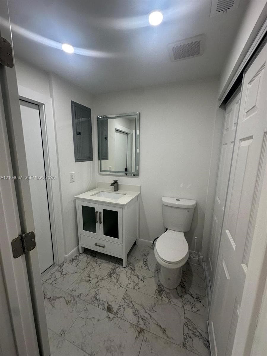 White vanity with glass-front cabinetry, undermount sink, and a framed mirror