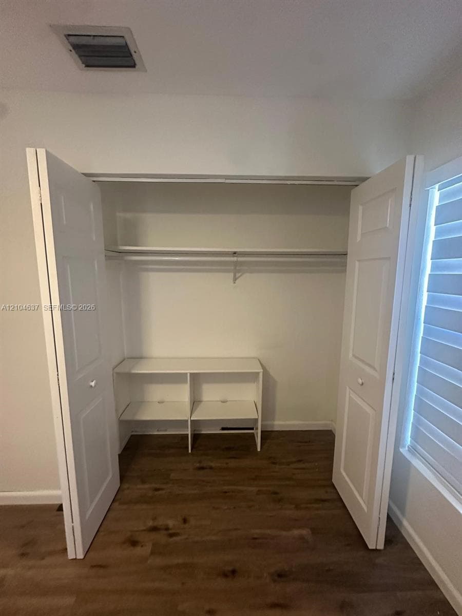 Integrated closet shelving with dual hanging rods, wood-finish flooring, and white bifold doors