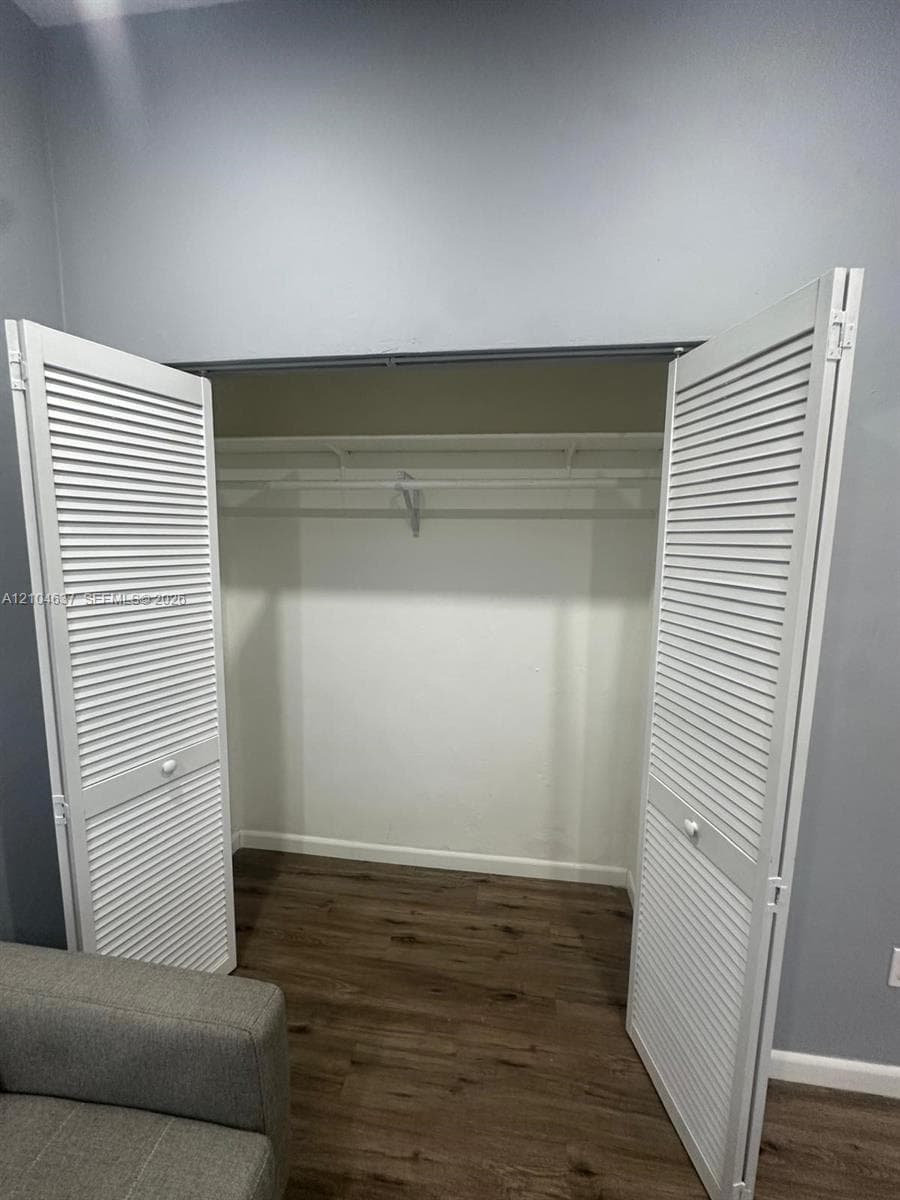 Closet featuring louvered bi-fold doors, a built-in hanging rod, and wood-finish flooring