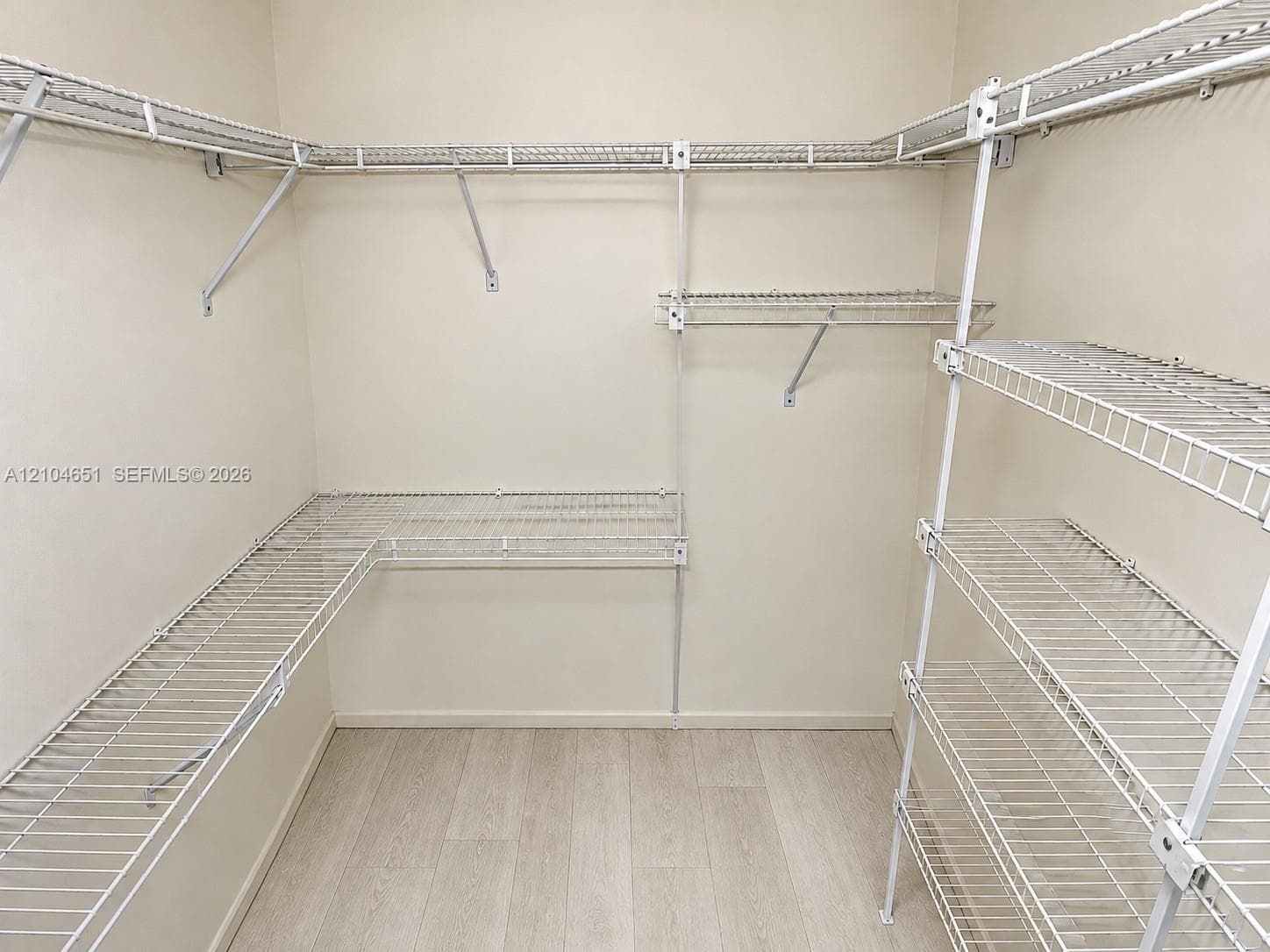 Walk-in storage space featuring wood-finish flooring and multi-level white wire shelving