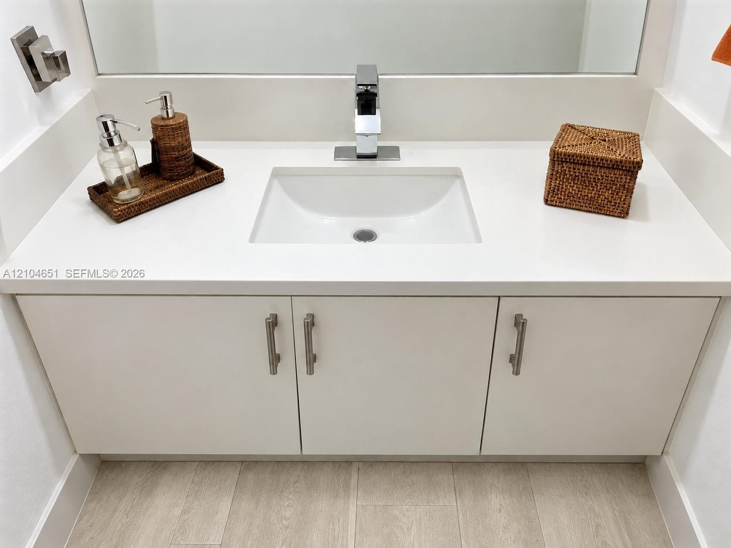Floating vanity featuring a solid-surface countertop, integrated rectangular sink, chrome single-handle faucet, and matte silver hardware