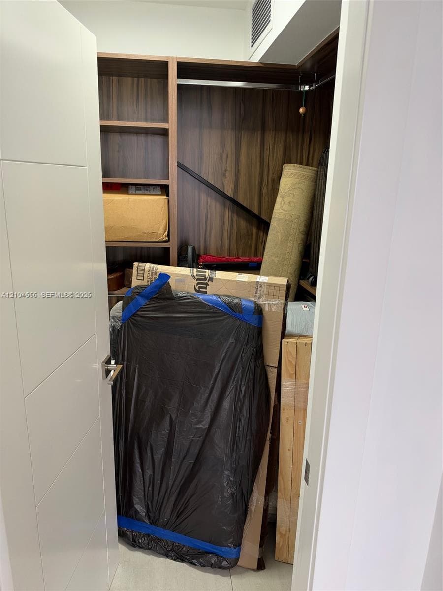 Custom closet featuring dark wood-finish cabinetry, built-in shelving, and metal hanging rods