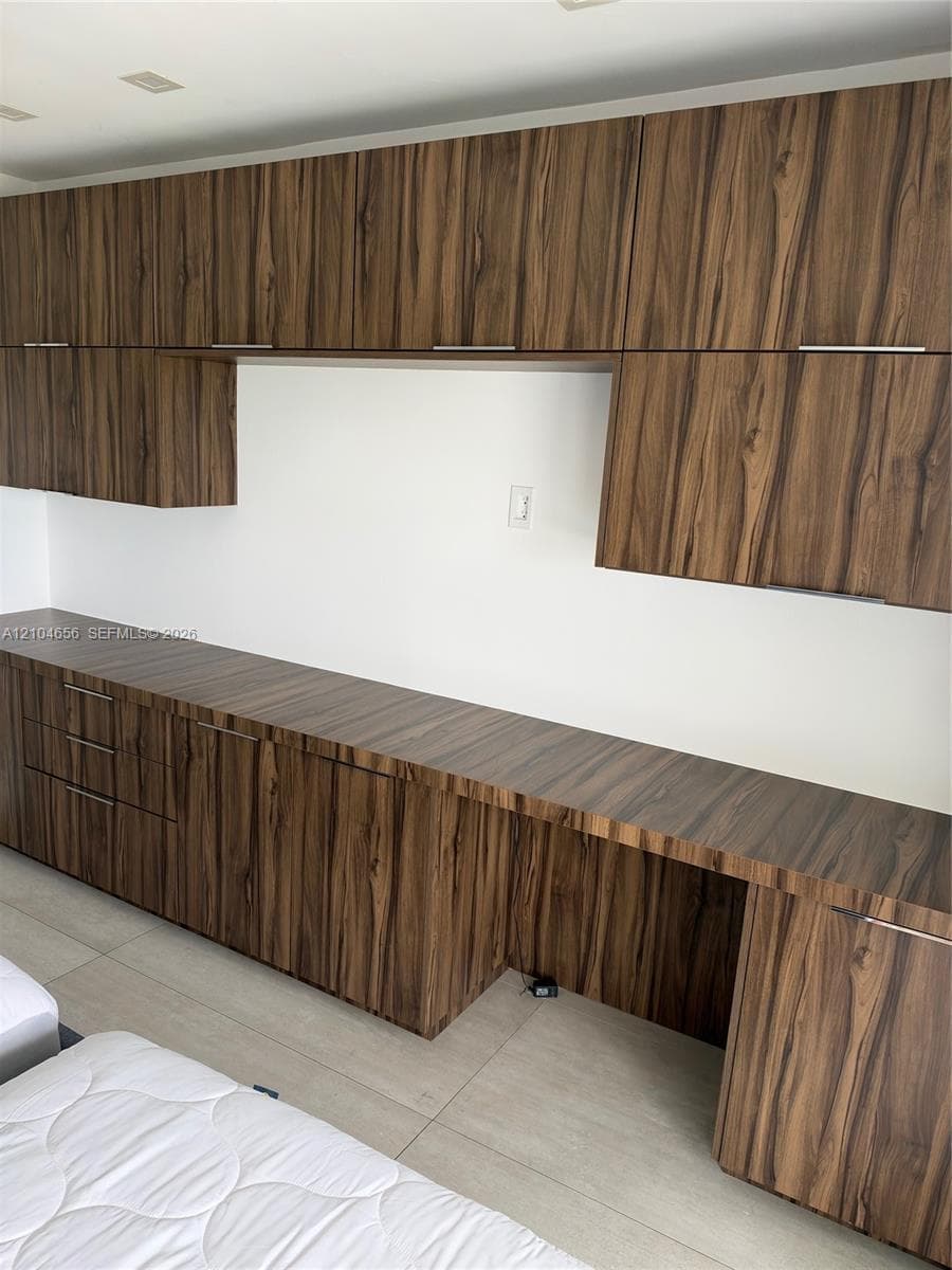 Custom built-in cabinetry featuring wood-finish cabinetry, sleek horizontal pulls, extensive countertop surface, and recessed ceiling lighting