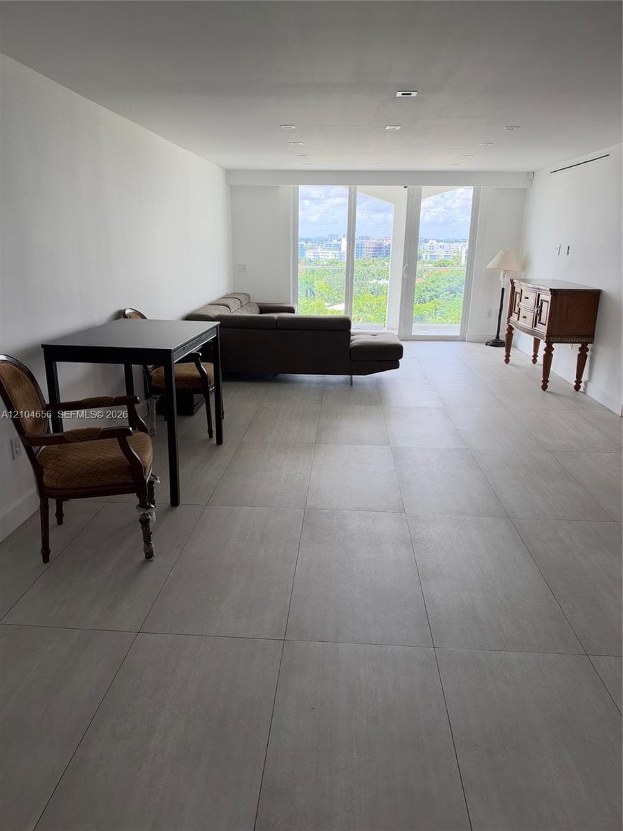 Large format tile flooring, recessed lighting, and floor-to-ceiling glass panel doors opening to an exterior balcony
