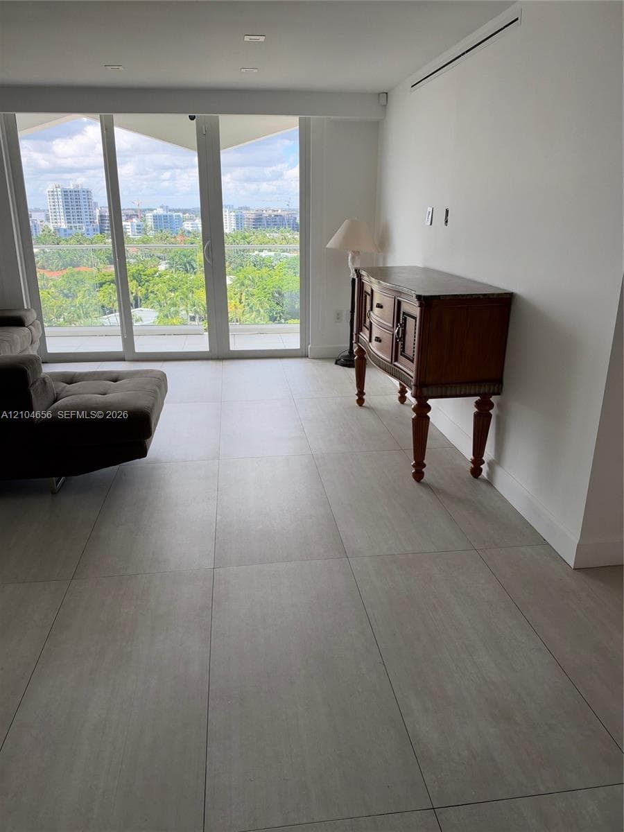 Large-format tile flooring, floor-to-ceiling glass sliding doors, recessed ceiling lighting, and urban scenery