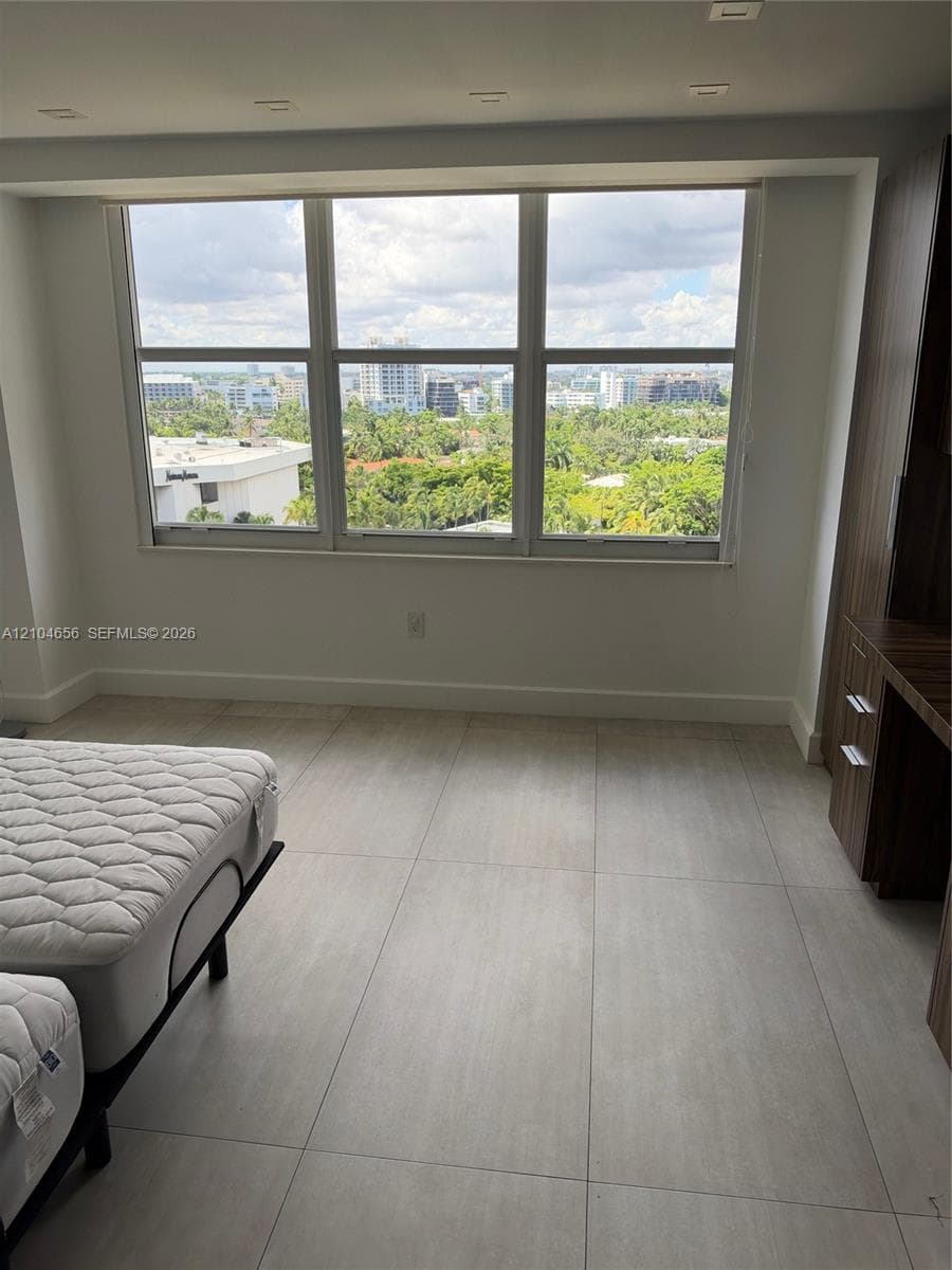 Large multi-pane window with expansive urban and landscape scenery, neutral ceramic tile flooring, and integrated wood-finish built-in cabinetry featuring drawer storage