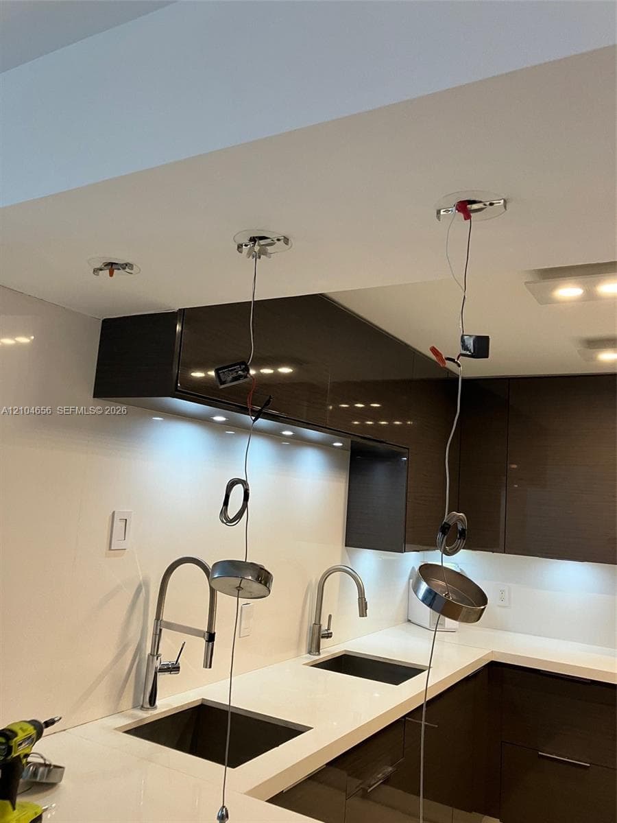 High-gloss cabinetry, solid-surface countertops, dual undermount sinks, and dual chrome gooseneck faucets
