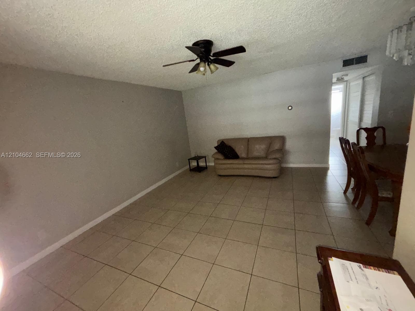 Spacious living area featuring tile flooring, a ceiling fan, and a neutral wall color