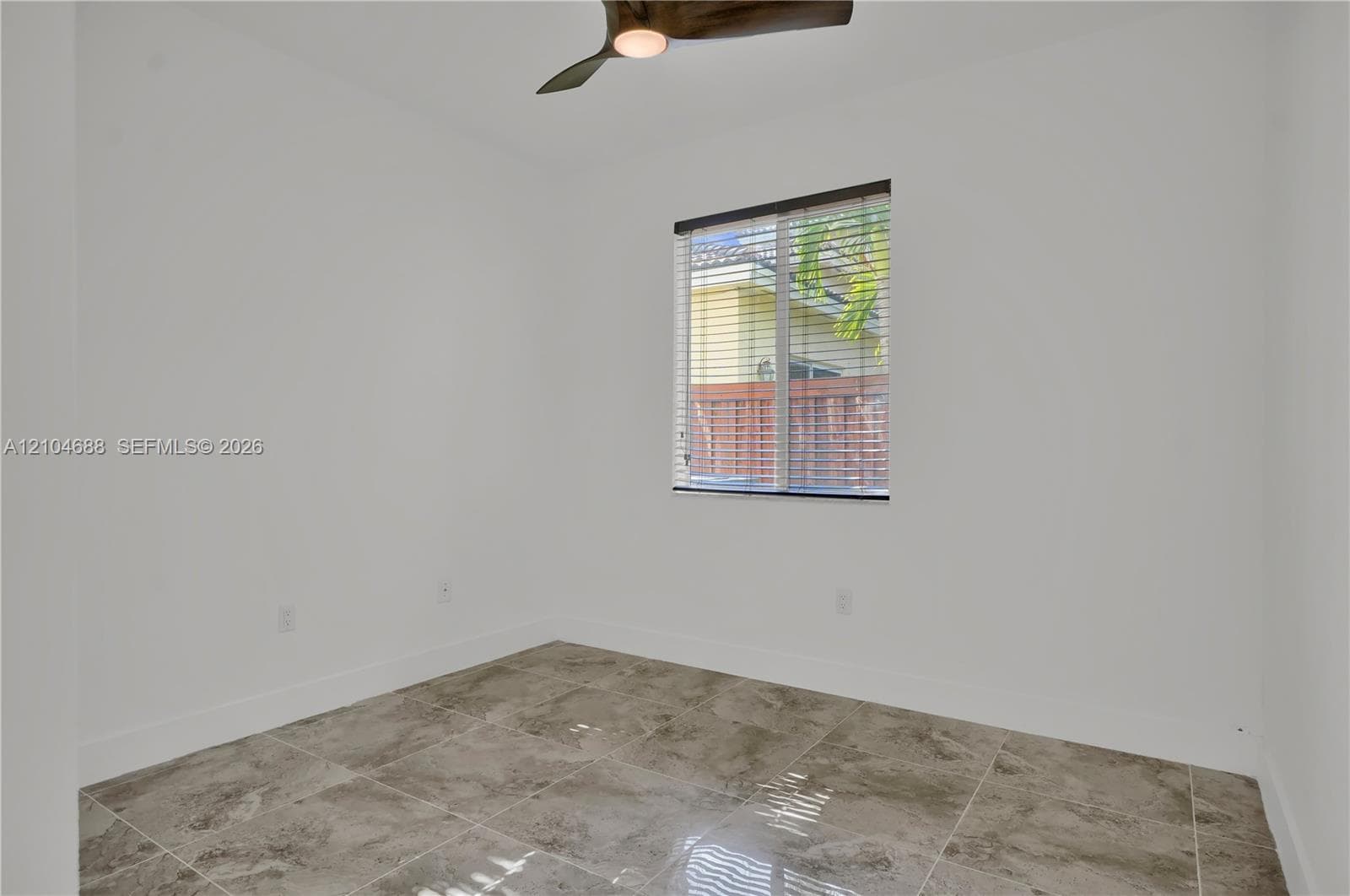 Interior space featuring large-format stone-finish flooring, a ceiling fan with integrated lighting, and a window with horizontal blinds