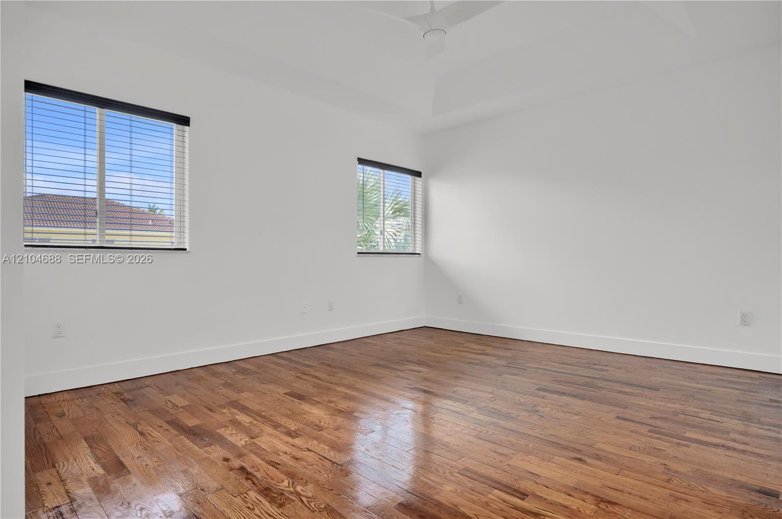 Room featuring wood-finish flooring, a tray ceiling, and dual windows
