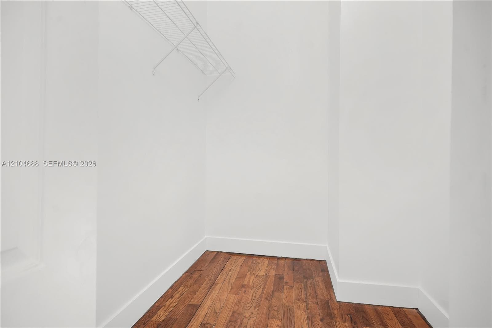 Storage area featuring wood-finish flooring and white walls with an integrated wire shelving rack