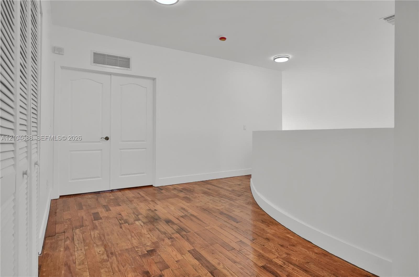 Wood-finish flooring, double-panel interior doors, and arched architectural wall detail