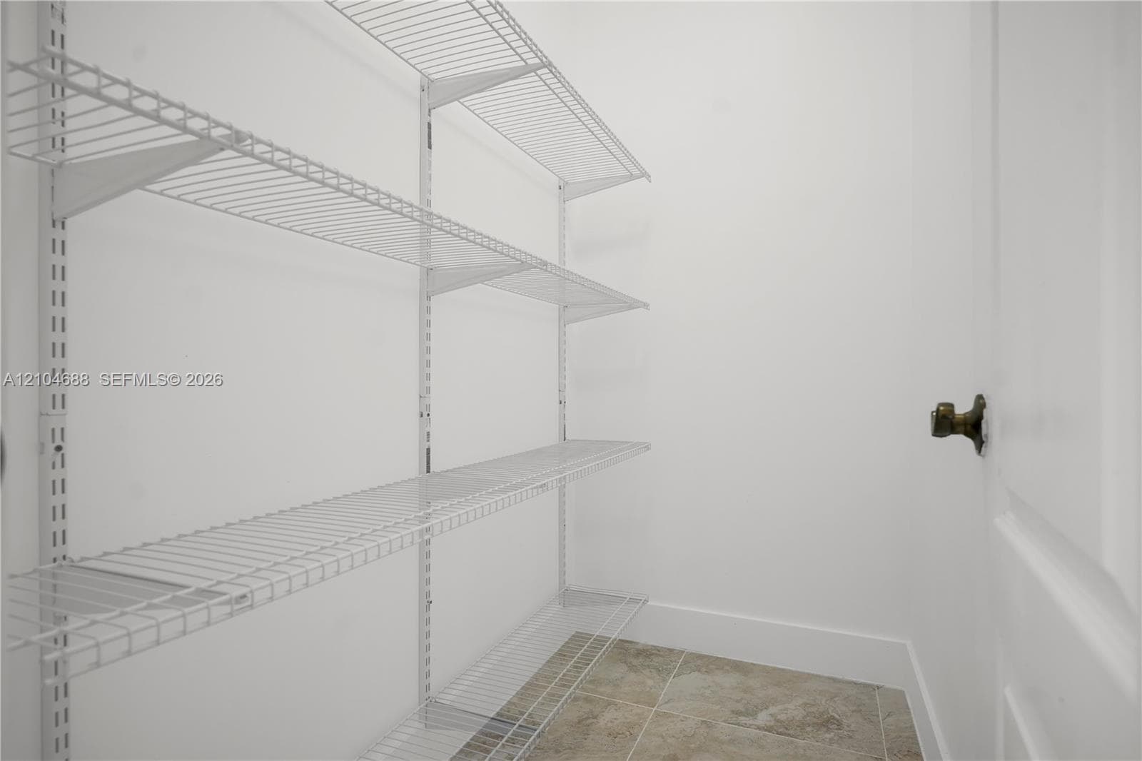 Storage area featuring white wire shelving units and tiled flooring