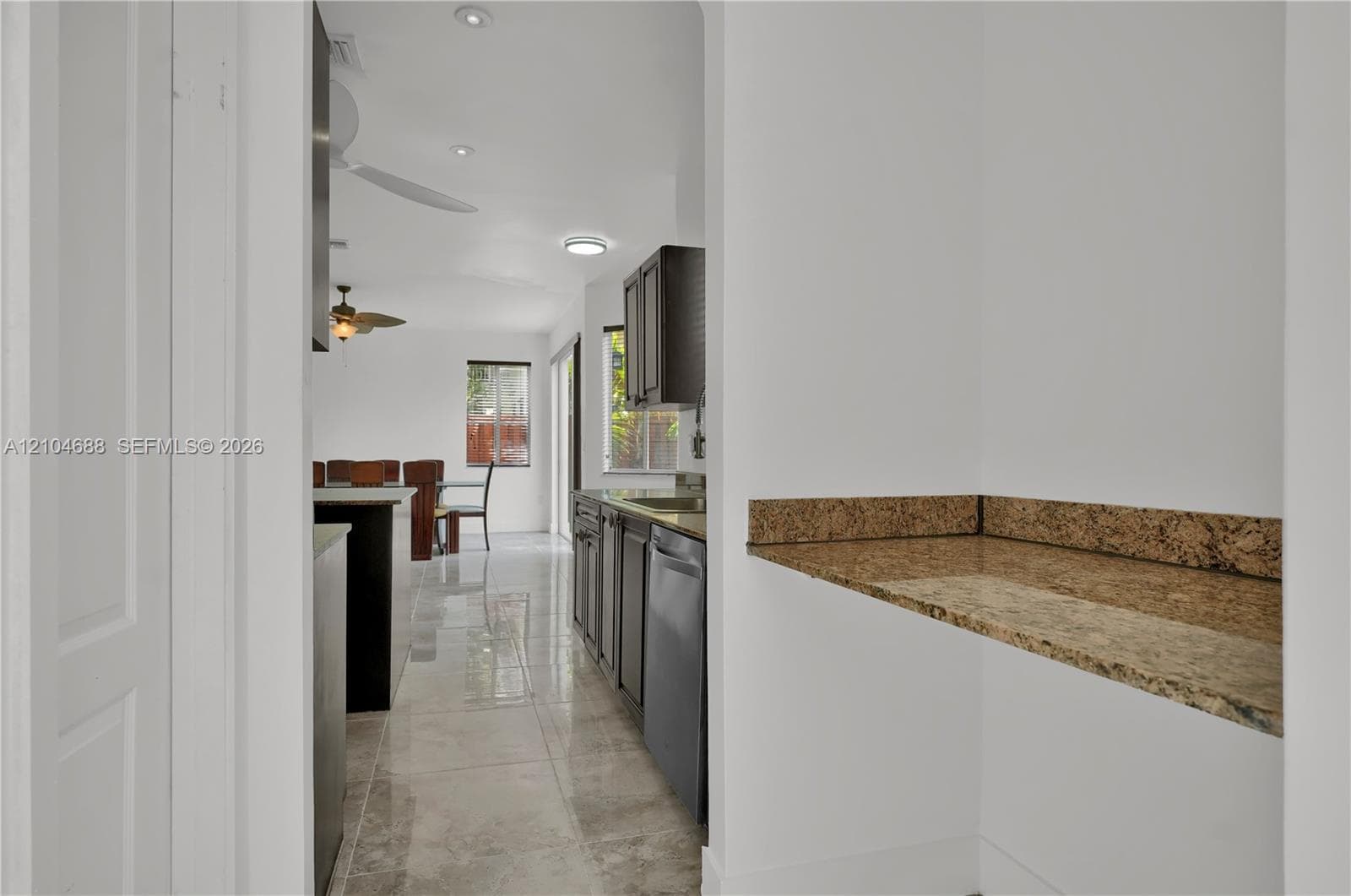 Kitchen featuring dark cabinetry, stone-surface counters, high-gloss tile flooring, and integrated ceiling lighting