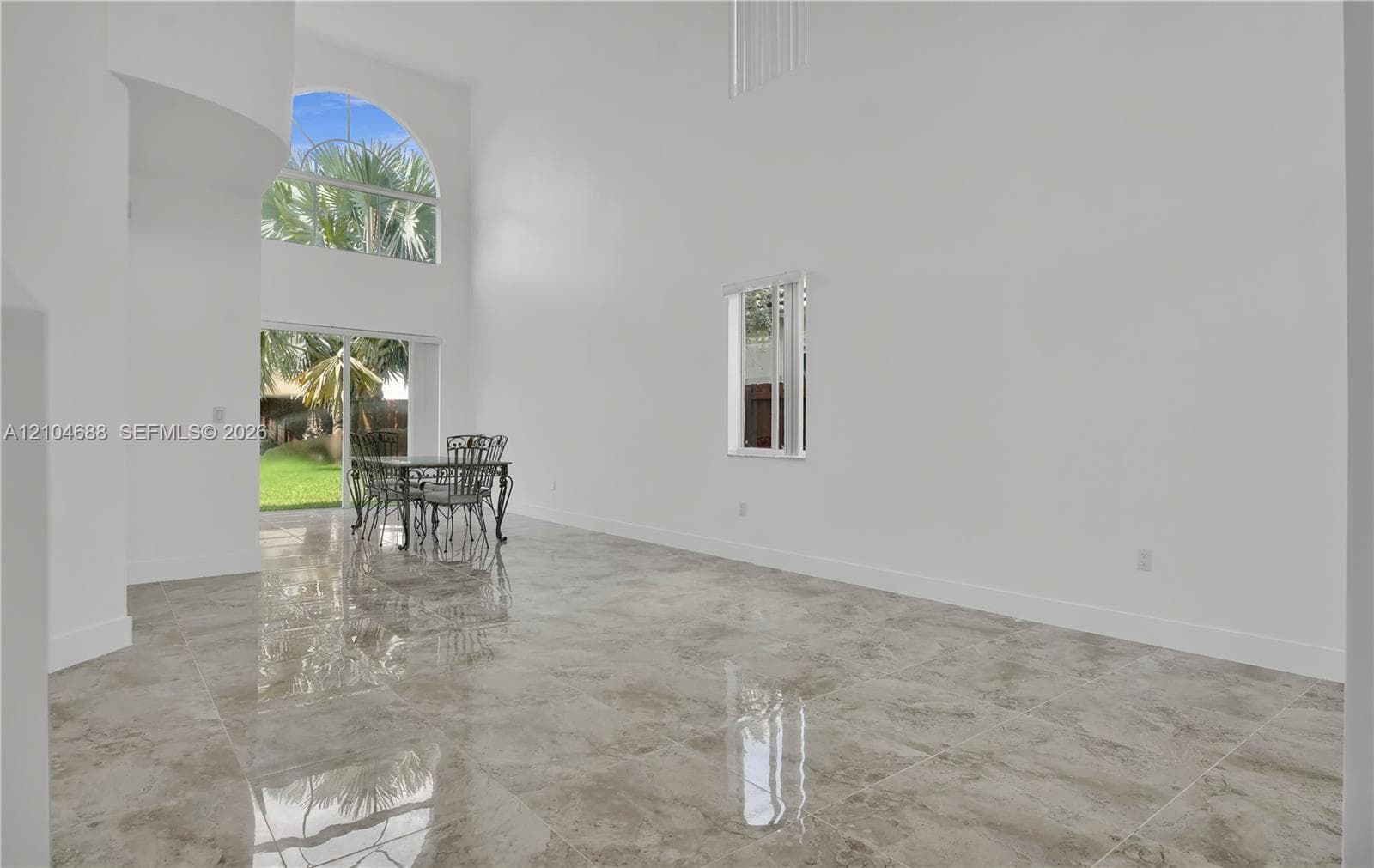 Double-height ceiling, large-format tile flooring, arched clerestory window, and sliding glass door